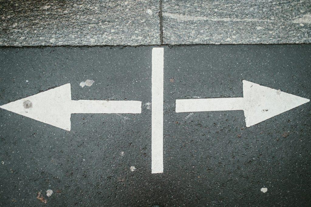 two white arrows pointing in opposite directions on asphalt